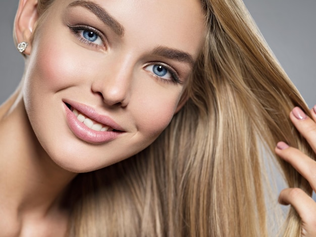 Photo gratuite jeune femme avec un beau sourire. visage d'un mannequin aux yeux bleus. jolie fille magnifique aux cheveux blonds - posant