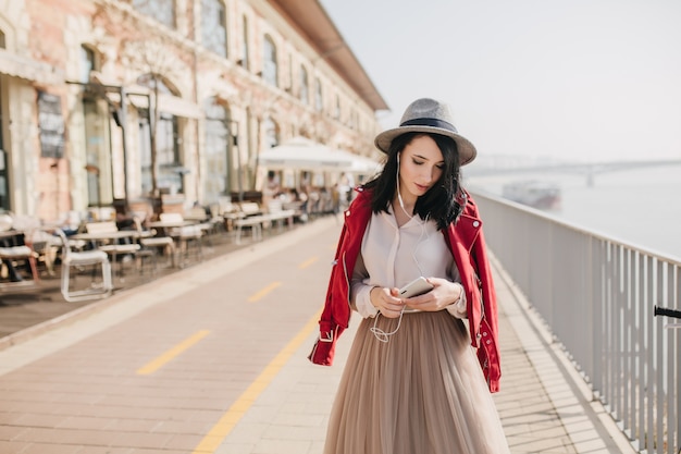 Jeune femme bien habillée au chapeau marchant dans la rue dans son temps libre