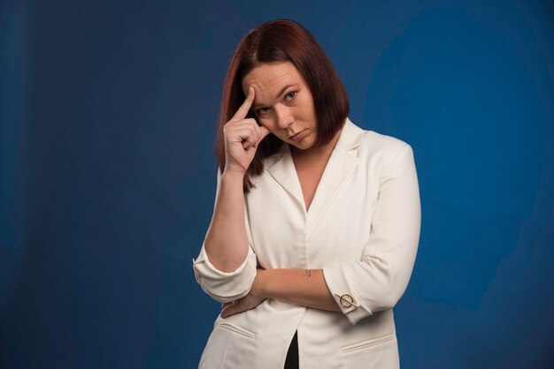 Jeune femme en blazer blanc a l'air réfléchie.