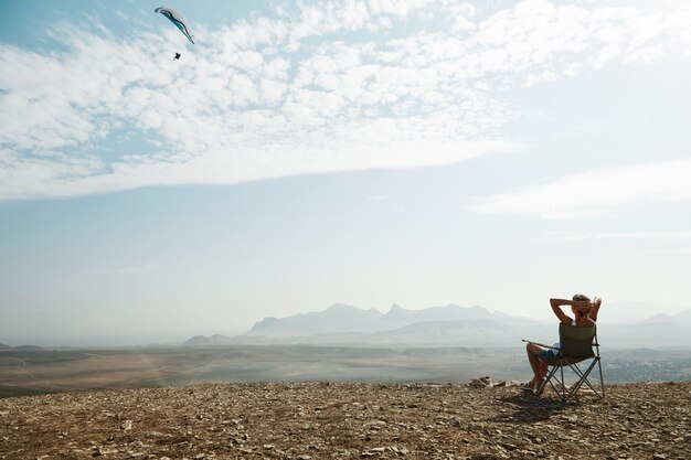 Jeune femme blonde assise au sommet de la colline