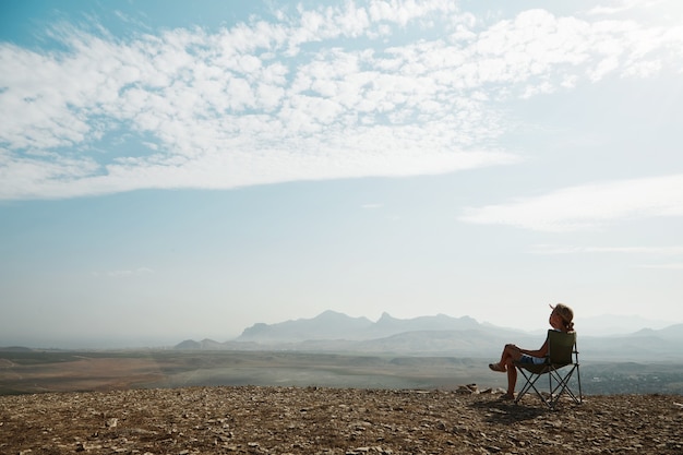 Jeune femme blonde assise au sommet de la colline