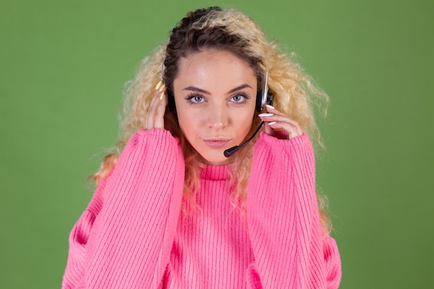 Photo gratuite jeune femme blonde aux longs cheveux bouclés en pull rose sur vert