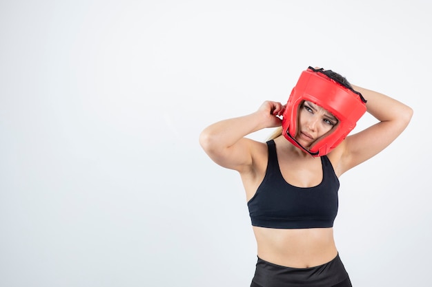 Jeune femme blonde en casque de boxe rouge posant.