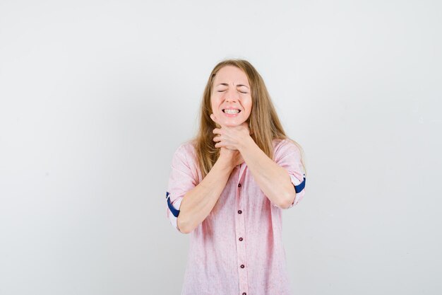 Jeune femme blonde dans une chemise rose décontractée ayant un mal de gorge