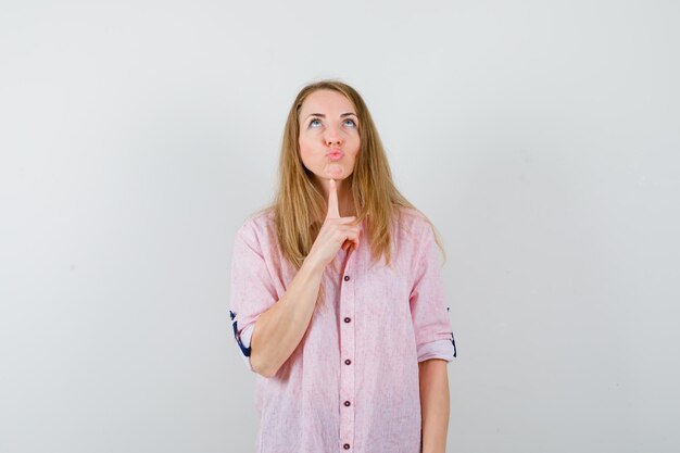 Jeune femme blonde dans une chemise rose décontractée