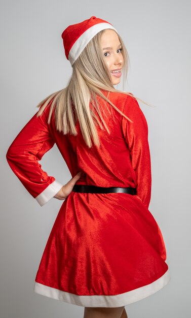Jeune femme blonde dans un costume de Miss Santa Claus tournant et regardant en arrière