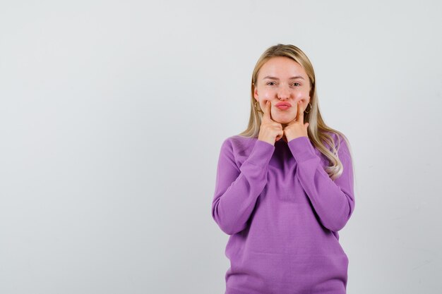 Jeune femme blonde dans un pull violet