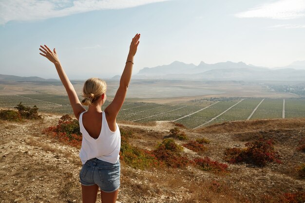 Jeune femme blonde debout au sommet de la colline