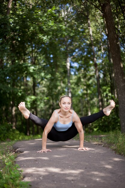 Jeune femme blonde faisant la posture de Firefly Yoga