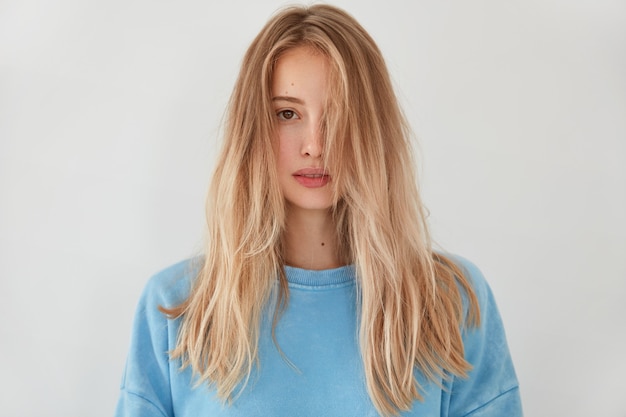 Jeune femme blonde portant un pull bleu