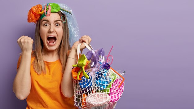 Jeune femme blonde posant avec des déchets plastiques