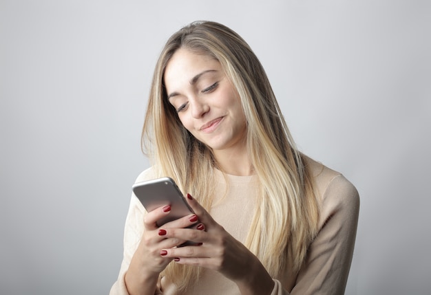 Jeune femme blonde regardant son téléphone et souriant