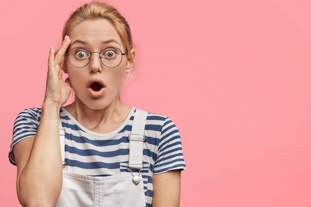 Jeune femme blonde en salopette et t-shirt rayé