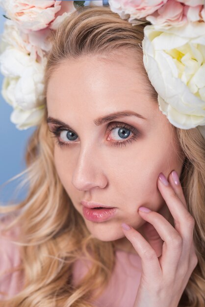 Jeune femme blonde sensuelle avec une couronne de belle fleur