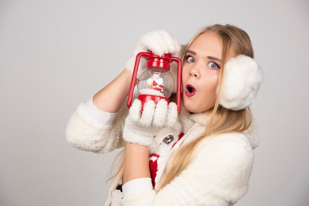 Jeune femme blonde en tenue blanche posant avec lampe de Noël.