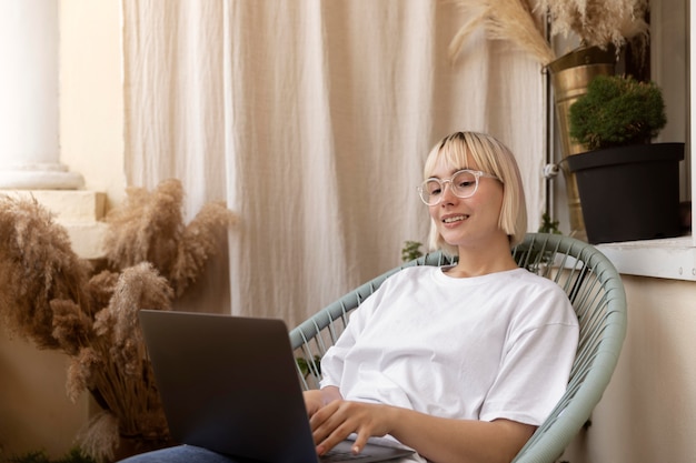 Jeune femme blonde travaillant à domicile sur sa chaise