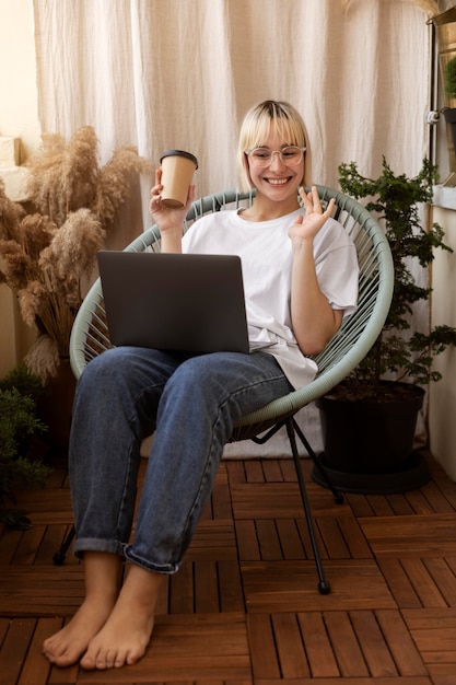 Jeune femme blonde travaillant à domicile sur sa chaise