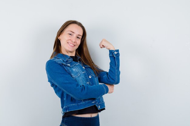 Jeune femme en blouse montrant le poing fermé et l'air confiant, vue de face.