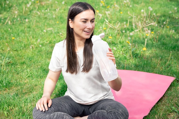Photo gratuite une jeune femme boit de l'eau après avoir fait de l'exercice à l'extérieur