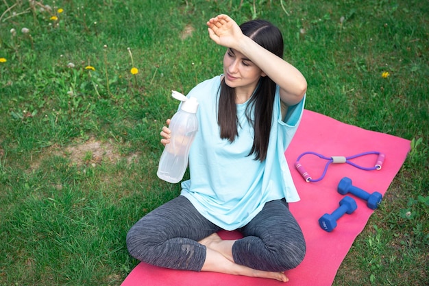 Photo gratuite une jeune femme boit de l'eau après avoir fait de l'exercice à l'extérieur