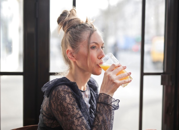 jeune femme boit un verre de soda à l'orange