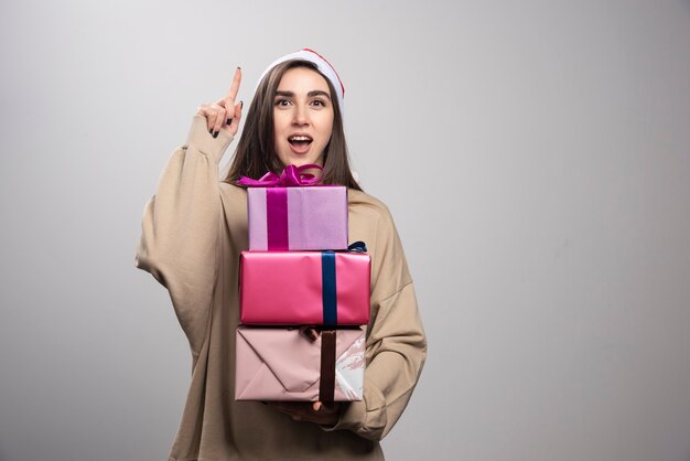 Jeune femme avec des boîtes de cadeaux de Noël pointant vers le haut.