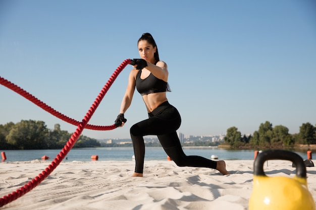 Jeune femme en bonne santé, faire de l'exercice avec les cordes à la plage