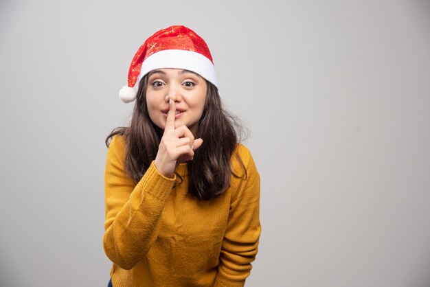 Jeune femme en bonnet de Noel faisant signe de silence.