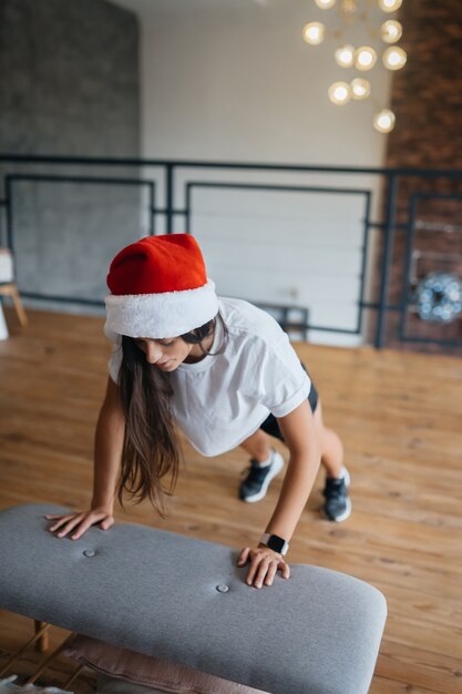 Jeune femme en bonnet de Noel pratiquant des exercices de gymnastique sportive