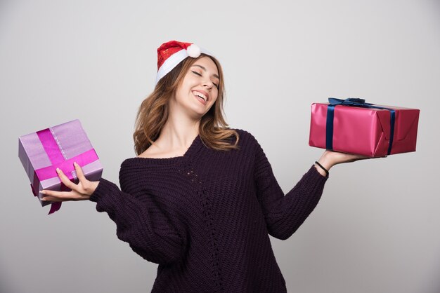 Jeune Femme Avec Bonnet De Noel Tenant Des Coffrets Cadeaux.