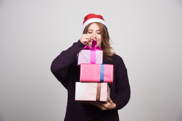 Jeune femme avec bonnet de Noel tenant des coffrets cadeaux.