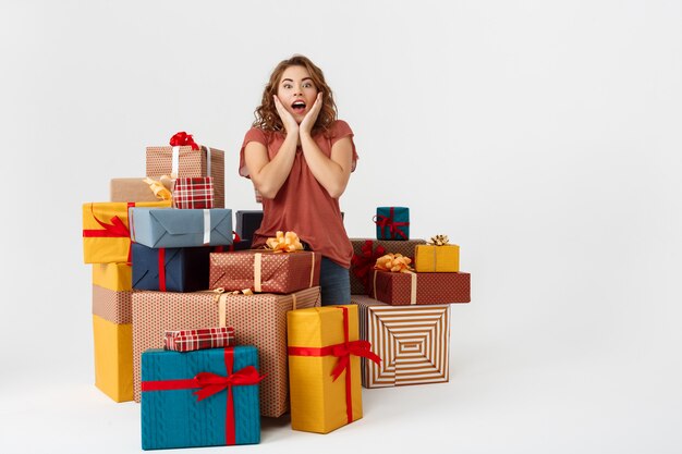 Jeune femme bouclée surprise parmi les coffrets cadeaux