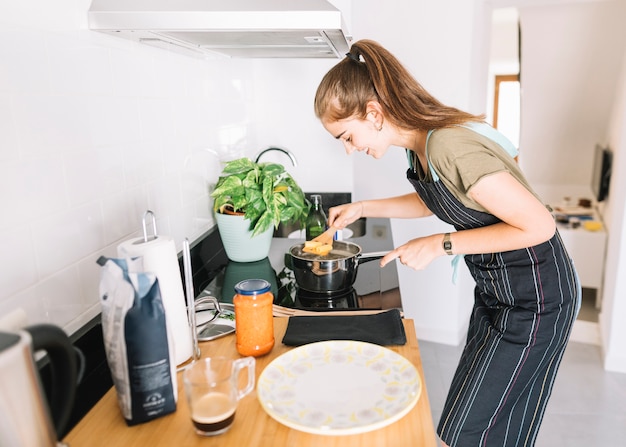 Jeune femme, bouillir, rigatoni, pâtes, dans, les, sauce, sur, les, cuisinière électrique