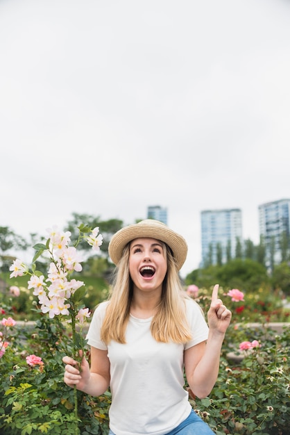 Jeune femme avec bouquet de fleurs, pointant le doigt vers le haut