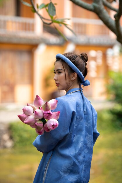 Jeune femme avec bouquet de fleurs portant un costume ao dai
