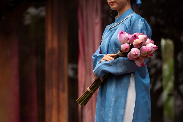 Jeune femme avec bouquet de fleurs portant un costume ao dai