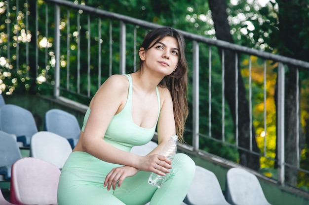 Une jeune femme avec une bouteille d'eau à l'entraînement au stade