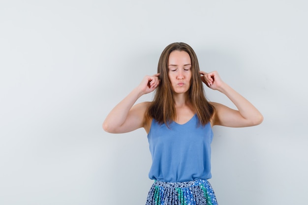 Photo gratuite jeune femme brancher les oreilles avec les doigts en maillot, jupe et à la détente