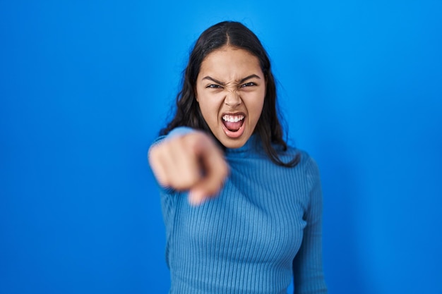 Photo gratuite jeune femme brésilienne debout sur fond bleu isolé pointant mécontent et frustré vers la caméra, en colère et furieux contre vous