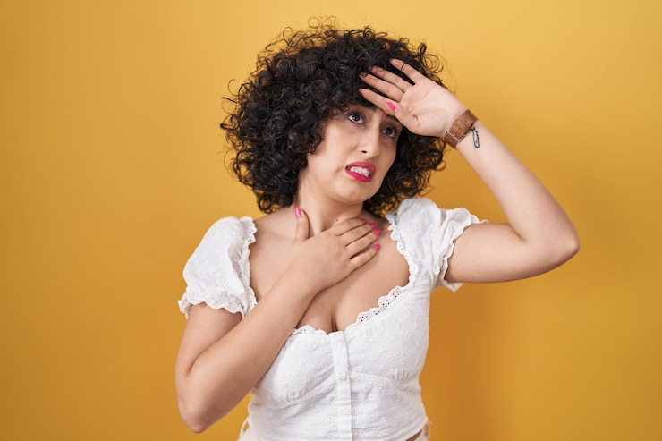 Photo gratuit jeune femme brune aux cheveux bouclés debout sur fond jaune touchant le front pour la maladie et la fièvre, la grippe et le rhume, le virus malade
