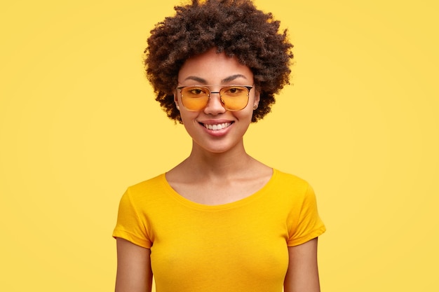 Jeune femme brune aux cheveux bouclés et lunettes à la mode