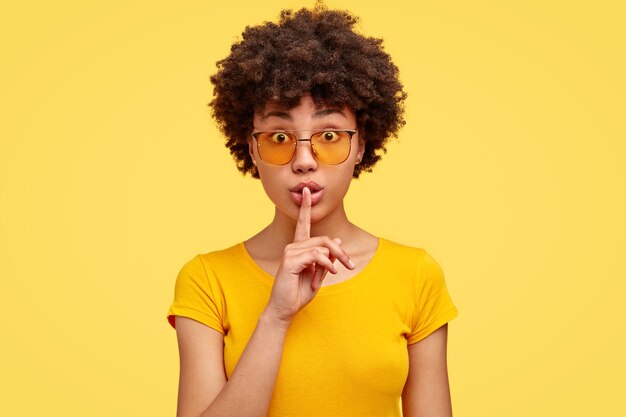 Jeune femme brune aux cheveux bouclés et lunettes à la mode