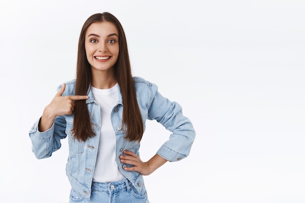 Jeune femme brune confiante et affirmée se pointant, se tenant droite avec la main sur la hanche comme parlant de réalisation personnelle, se vantant ou se vantant, bénévole, veut devenir candidate