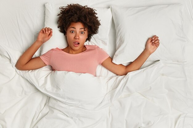 Jeune femme brune couchée dans son lit