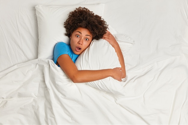 Jeune femme brune couchée dans son lit