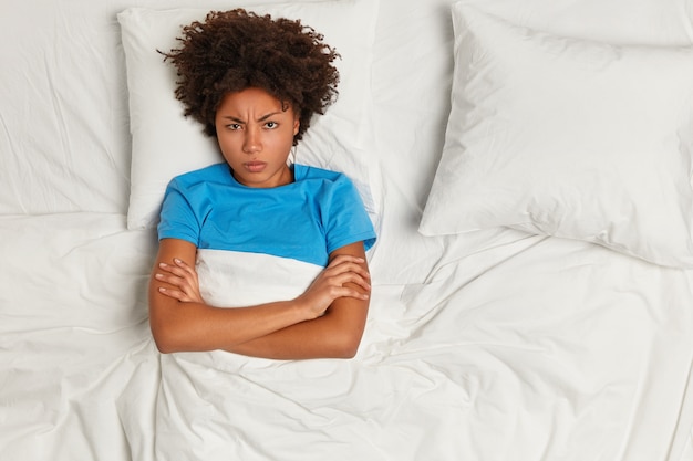 Jeune femme brune couchée dans son lit