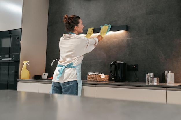 Jeune femme brune nettoyant la lampe dans la cuisine