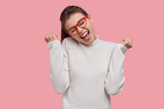 Jeune femme brune portant un pull blanc et des lunettes rouges