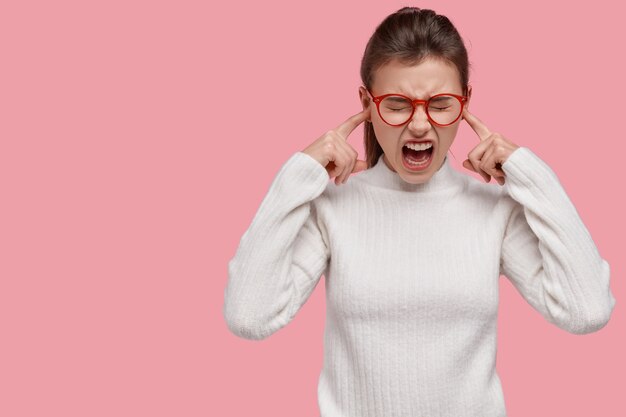 Jeune femme brune portant un pull blanc et des lunettes rouges