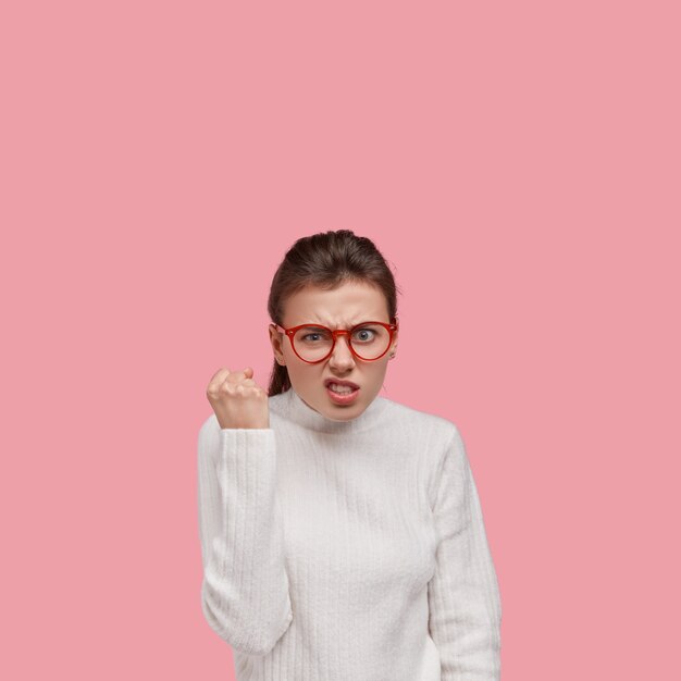 Jeune femme brune portant un pull blanc et des lunettes rouges